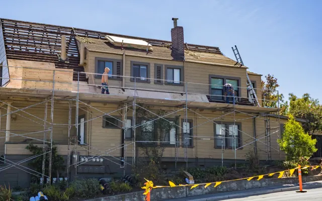 Maison en cours de rénovation avec échafaudage et ouvriers sur la toiture